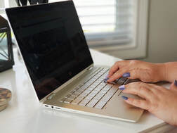 Picture of a laptop computer with hands typing that represents our work